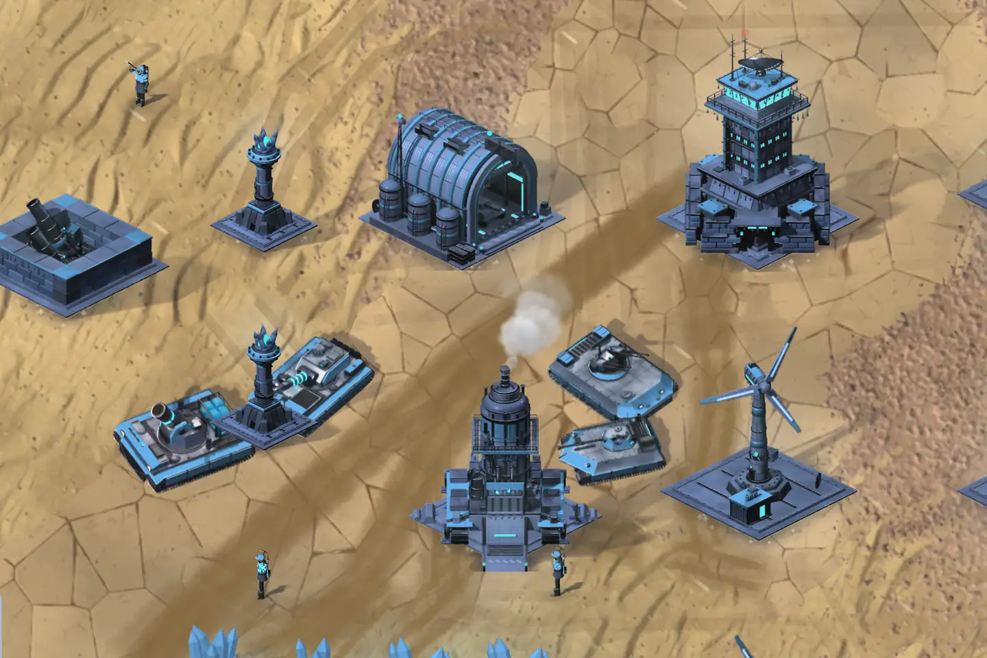 A FROST base on desert sand, seen from above, its buildings dark steel picked out in glowing cyan: a tall tower with a radar dish, a ribbed hangar, a spired building trailing steam, two slim towers crowned with ice, a wind turbine and a square gun pit. Four blue-and-grey tanks are parked among them, and a few soldiers walk between.