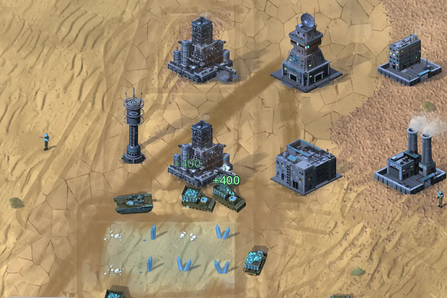 Harvesters at work on desert sand, seen from above. Two tracked trucks are tipping heaped cyan loads into a refinery, and a green +400 floats over each; another loaded truck works a field of pale blue crystals, mined nearly flat, below. Around them stand dark steel buildings: a tower with a radar dish, an office block, a power plant with twin smoking stacks and a slim tower, with a tank and two soldiers nearby.