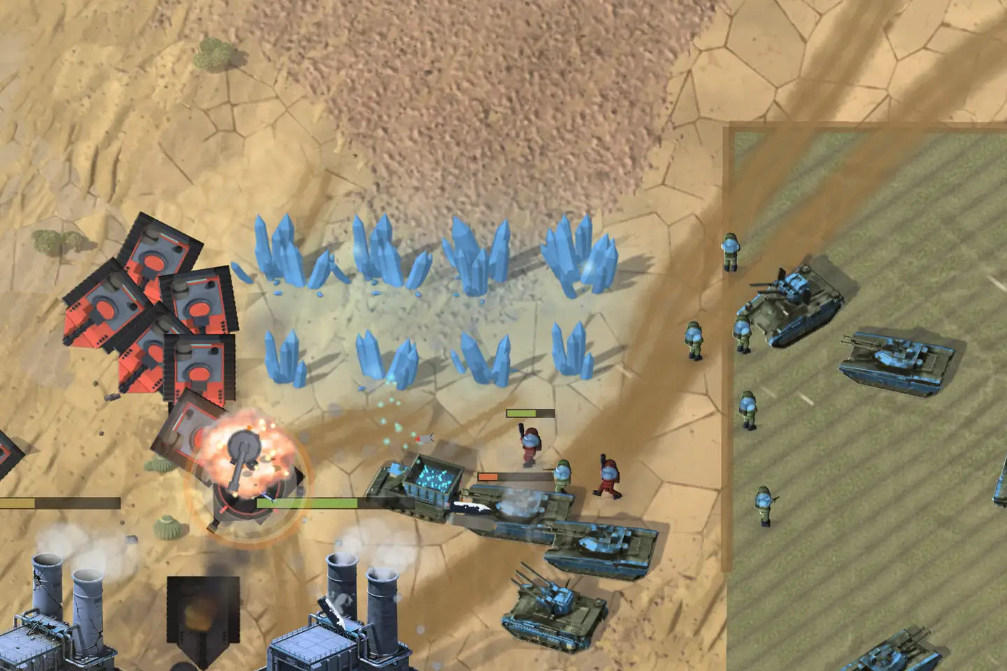 An online battle on desert sand, seen from above. Squat black-and-red tanks crowd in from the left past a field of pale blue crystals, one of them caught in an orange blast; olive tanks with blue domes and infantry hold a striped green field on the right, and two power plants with twin smoking stacks stand at the bottom left.